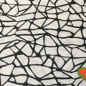 May include: Black and white fabric with a geometric pattern of intersecting lines forming irregular shapes.