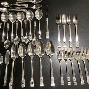May include: A set of silverware, including forks, spoons, and a butter knife, all with ornate handles. The silverware is made of polished silver and has a classic design.