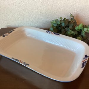 May include: White rectangular baking dish with a blue and orange floral design around the rim.