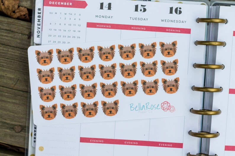 May include: A sheet of 18 brown and black Yorkshire Terrier dog stickers. The stickers are arranged in a grid pattern on a white background. The stickers are approximately 1 inch in diameter.