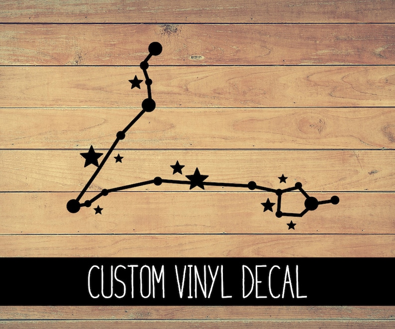 May include: Black vinyl decal of the Pisces constellation on a wood background. The decal features a stylized outline of the constellation with small stars. The text "CUSTOM VINYL DECAL" is printed below the constellation.
