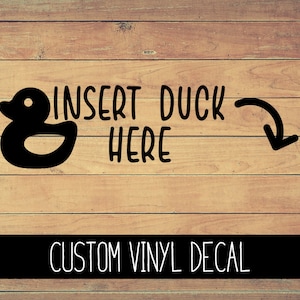 May include: A black and white vinyl decal with the text "Insert Duck Here" and a cartoon rubber duck illustration. An arrow points to the right.