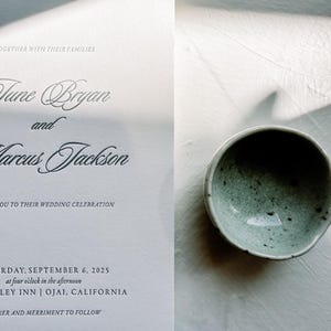 May include: A wedding invitation with elegant script, featuring the names June Bryan and Marcus Jackson. The invitation includes the date, time, and location: Saturday, September 6, 2025, at four o'clock in the afternoon, at the Ojai Valley Inn in Ojai, California. A small, speckled, light green bowl is in the image.