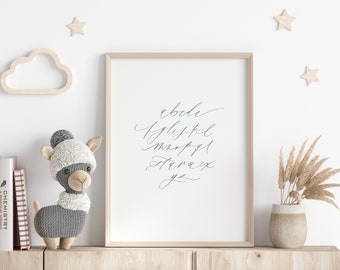 May include: A framed print with a white background and blue calligraphy of the alphabet. The print is hanging on a white wall with a wooden cloud and stars above it. A gray knitted llama toy is on a wooden shelf below the print.