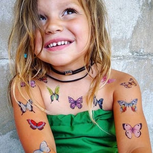 Girl wearing butterflies temporary tattoo transfers. Big set of 21 watercolor butterfly body stickers for kids.