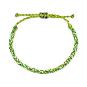 Può includere: Braccialetto verde intrecciato con chiusura a nodo regolabile. Il braccialetto presenta un mix di fili verdi chiari e scuri, creando un design strutturato e colorato. La chiusura regolabile consente una vestibilità confortevole. Un accessorio alla moda.