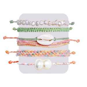 May include: Set of five colorful bracelets with shell and pearl charms. The bracelets are made of woven string and beads.
