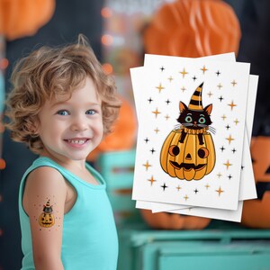 May include: A child wearing a blue tank top has a temporary tattoo on their arm. The tattoo is a black cat wearing a witch's hat sitting inside a jack-o'-lantern. The image shows a sheet of temporary tattoos with the same design.