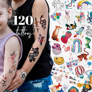 Könnte beinhalten: Eine Sammlung von 120 temporären Tattoos mit verschiedenen Designs. Die Tattoos zeigen Blumenarrangements, Totenköpfe, eine Schlange, eine Rose, ein Skateboard mit "Skate or Die", einen Fuchs, einen Regenbogen, einen Tiger und ein Smiley-Gesicht.