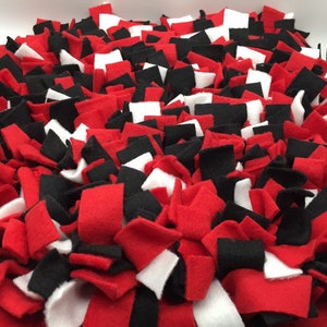 May include: A red, black, and white felt dog toy. The toy is made of many small pieces of felt that are knotted together. This is a great way to keep your dog entertained and engaged.