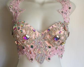 May include: A pink lace bralette with iridescent rhinestones and a delicate floral design. The bralette has adjustable straps and a hook and eye closure.