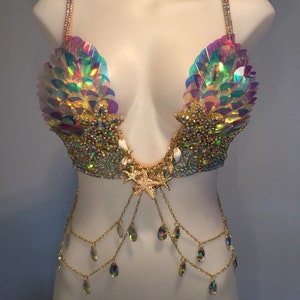 May include: A mermaid-themed bra top with iridescent sequins, gold chains, and crystal accents. The bra top features a seashell design and a starfish pendant.