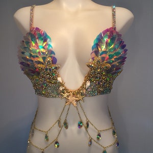 May include: A mermaid-themed bra top with iridescent sequins, gold chains, and crystal accents. The bra top features a starfish design in the center and seashell accents.