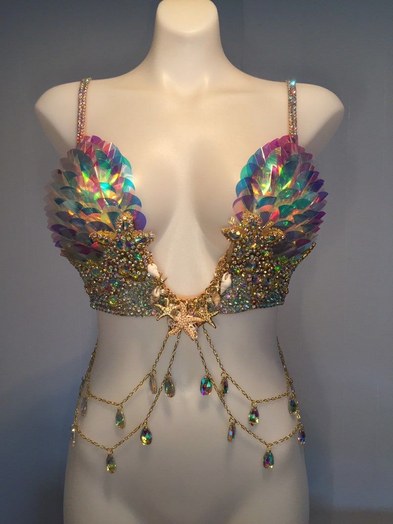 May include: A mermaid-themed bra top with iridescent sequins, gold chains, and crystal accents. The bra top features a starfish design in the center and seashell accents.