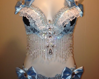 May include: A blue and black lingerie set with lace trim and crystal embellishments. The set includes a bra with a beaded fringe and a matching panty with a bow on each side.