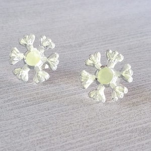Peut inclure: Une paire de boucles d'oreilles en forme de flocon de neige argentées avec une pierre centrale blanche.