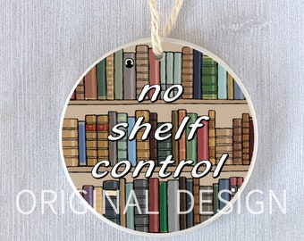 Puede incluir: Adorno redondo de cerámica con un diseño de estantería y el texto "no shelf control". El adorno es blanco con una estantería marrón y libros coloridos. Tiene una cuerda para colgar.