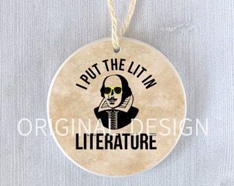 Può includere: Ornamento rotondo in ceramica con sfondo beige e un'immagine in bianco e nero di William Shakespeare con occhiali da sole gialli. Il testo "I PUT THE LIT IN LITERATURE" è stampato sopra l'immagine. Un anello di spago naturale è attaccato per appenderlo.