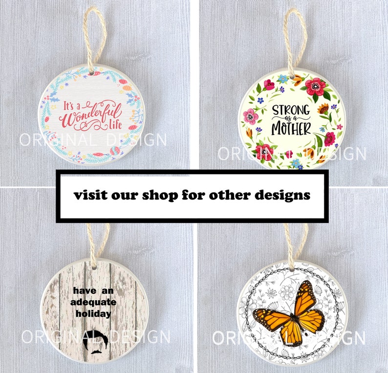 Op de afbeelding: Vier ronde keramische ornamenten met verschillende ontwerpen. De eerste ornament is wit met een roze bloemenkrans en de tekst "It's a Wonderful Life". De tweede ornament is wit met een roze, gele en blauwe bloemenkrans en de tekst "Strong as a Mother". De derde ornament is wit met een houtnerf achtergrond en de tekst "have an adequate holiday". De vierde ornament is wit met een zwart-witte bloemenkrans en een monarchvlinder.