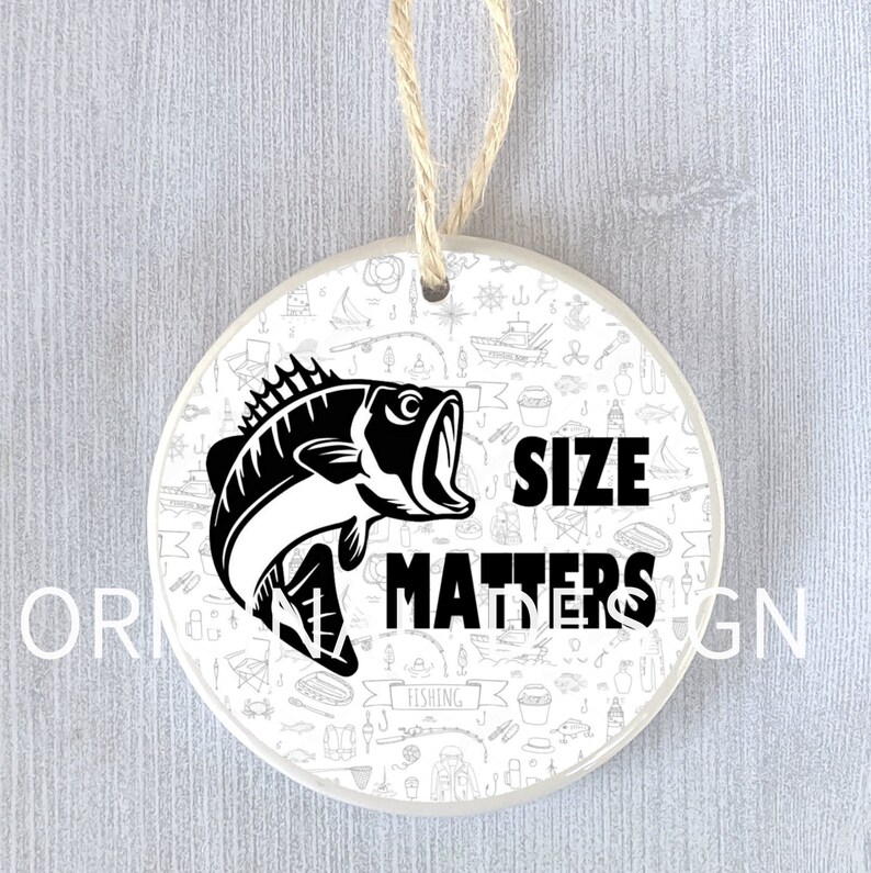 Op de afbeelding: Een witte keramische ornament met een zwart-witte illustratie van een vis en de tekst "Size Matters" op een witte achtergrond met een vis-thema.