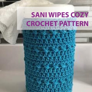 Pode incluir: Uma capa de crochê azul para um recipiente de toalhetes desinfectantes. A capa é feita com um ponto texturizado e tem uma faixa de crochê branca ao redor da parte superior. O texto "Sani Wipes Cozy Crochet Pattern" é exibido na imagem.