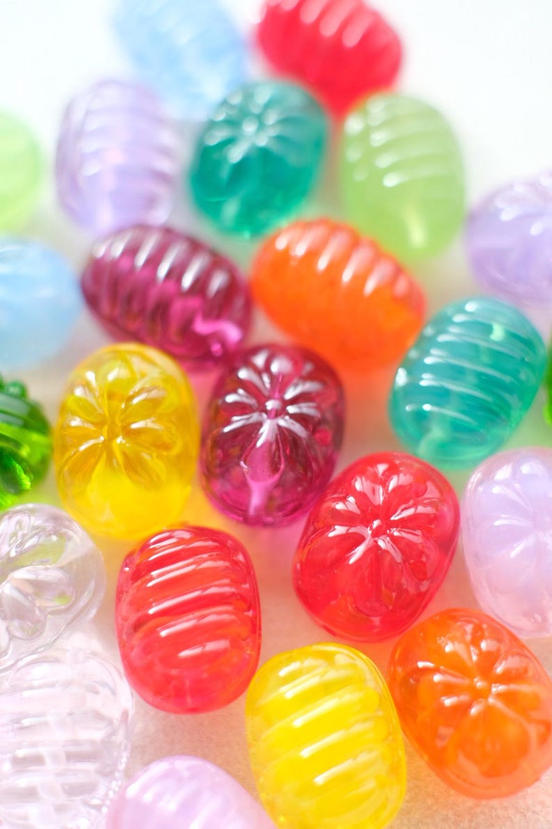 May include: A collection of colorful, translucent, oval-shaped candies. The candies are in various colors, including red, orange, yellow, green, purple, and blue. Some candies have a ribbed texture, while others have a flower-like design.