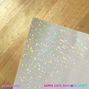 May include: White iridescent glitter paper with a subtle sparkle. The paper has a smooth, slightly textured surface. The text "SUPER CUTE AWESOME STUFF" is printed in the bottom right corner.