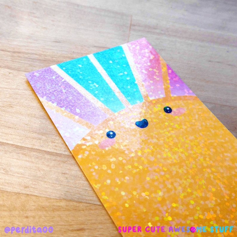 May include: A yellow, glittery sun with a rainbow of colors behind it. The sun has a happy face with two eyes and a smile. The text "SUPER CUTE AWESOME STUFF" is at the bottom of the image.