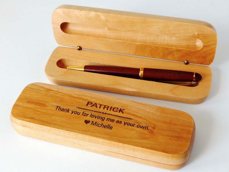May include: A wooden pen case with a dark brown pen inside. The pen has gold accents and the name "PATRICK" engraved on it. The case is open, revealing the pen, and the lid is engraved with a message and the name "PATRICK".
