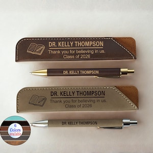May include: A set of personalized pens and cases in brown and tan leather. The cases have the text "DR. KELLY THOMPSON" and "Thank you for believing in us. Class of 2026." A color chart shows six available colors.