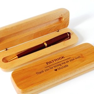 May include: A personalized pen with the name "PATRICK" engraved on the pen and the wooden case. The pen is dark red with gold accents, presented in an open, light-colored wooden case. The case is engraved with a message.