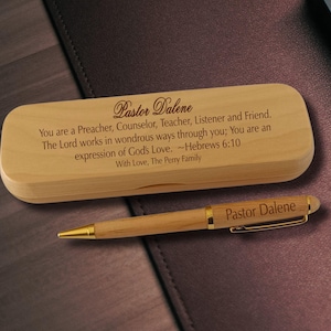 May include: A light-colored wooden pen case and a matching wooden ballpoint pen with gold-tone accents. The case is engraved with: Pastor Dalene, You are a Preacher, Counselor, Teacher, Listener and Friend. The Lord works in wondrous ways through you; You are an expression of God's Love. ~Hebrews 6:10, With Love, The Perry Family. The pen is engraved with Pastor Dalene.