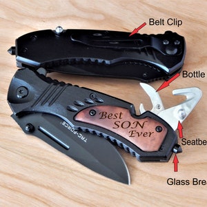 May include: Two black pocket knives with a wood handle. The top knife has a belt clip and a bottle opener. The bottom knife has a seatbelt cutter, a glass breaker, and a wood handle with the words "Best Son Ever" engraved on it.