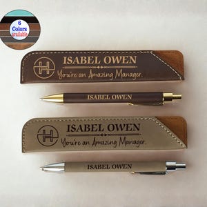 Op de afbeelding: Twee gepersonaliseerde pennen en pennenzakken. De pennen en etuis zijn bruin en beige met de naam "ISABEL OWEN" en de boodschap "You're an Amazing Manager" gegraveerd. Een kleurenpalet toont zes beschikbare kleuren.
