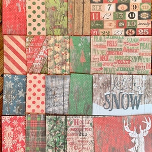May include: A set of 25 Christmas themed paper squares with various designs, including red and white stripes, red and white polka dots, snowflakes, plaid, and wood grain patterns. The squares feature Christmas-related words and phrases like "Let it Snow", "Jingle Bells", "Merry Christmas", and "Peace on Earth".