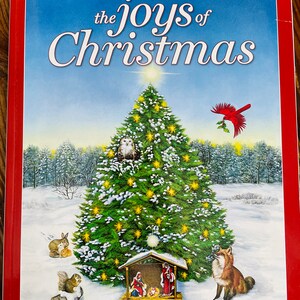 May include: A red book with the title "Guideposts the joys of Christmas" on the cover. The cover features a snowy winter scene with a Christmas tree, a nativity scene, a cardinal, a fox, a squirrel, and a rabbit.