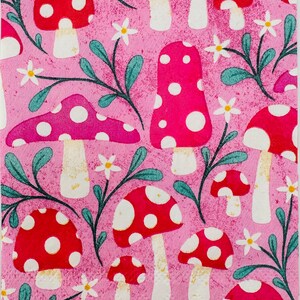 May include: Pink background with a repeating pattern of red and white mushrooms with white dots. The mushrooms have a white stem and a red cap with white dots. There are also green leaves and white flowers in the pattern.