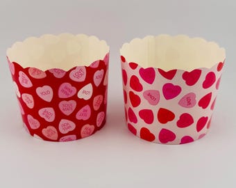 May include: Two red and pink cupcake liners with a heart pattern and the words "Love", "Wink", "Soul Mate", "True Love", "Miss You", "Real Love", "Text Me", "Sweet", "You", "Baby", "Yolo", and "Love You" printed on them.