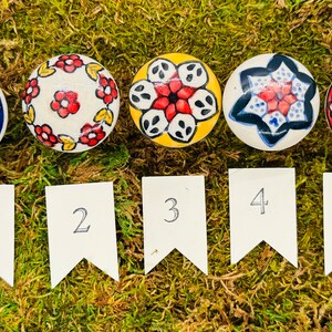May include: Five ceramic knobs with colorful floral and geometric patterns. The knobs are numbered 1 through 5.
