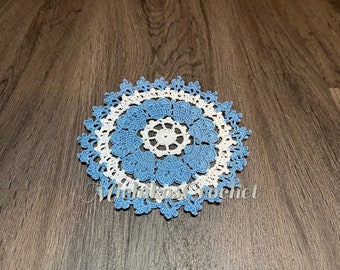 May include: A blue and white crocheted doily with a delicate floral pattern. The doily is made with a fine yarn and has a delicate, lacy look.