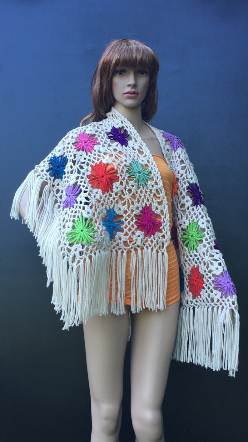 May include: White crochet shawl with colorful flower accents and fringe.