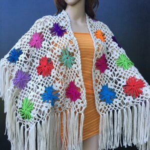 May include: White crochet shawl with colorful flower accents and fringe trim.