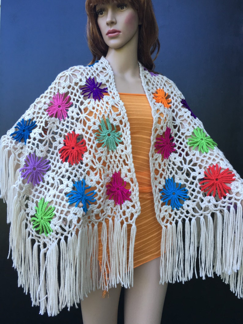 May include: White crochet shawl with colorful flower accents and fringe trim.