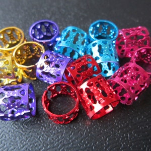 May include: A collection of colorful metal hair beads in purple, blue, red, and gold. The beads have a decorative, openwork design.