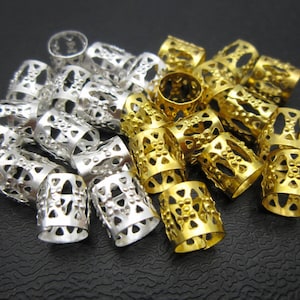 May include: A close-up of a pile of gold and silver hair beads. The beads are made of metal and have a decorative design.