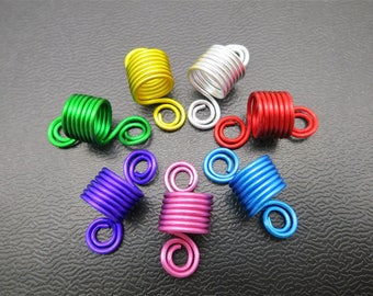 Peut inclure: Un ensemble de dix spirales pour cheveux de différentes couleurs, en fil métallique, comprenant du vert, du jaune, du rouge, du bleu, du violet et de l'argent. Les spirales sont conçues pour aider à créer et à maintenir des boucles dans les cheveux.