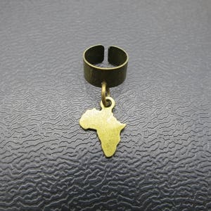 Op de afbeelding: Een gouden oormanchet met een hangende bedel in de vorm van het Afrikaanse continent.