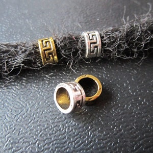 May include: Four silver and gold metal beads with a geometric design. The beads are for dreadlocks.