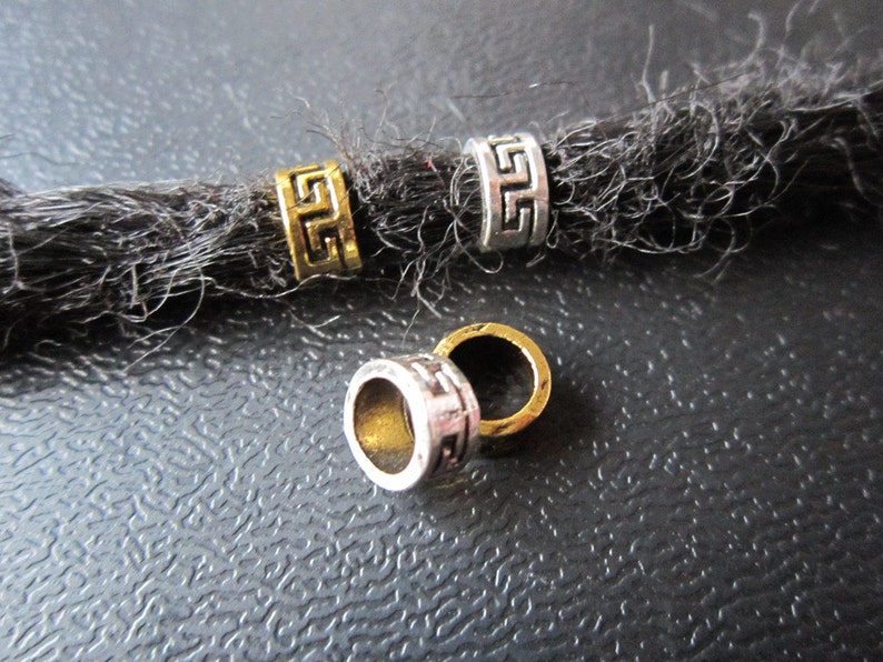 May include: Four silver and gold metal beads with a geometric design. The beads are for dreadlocks.