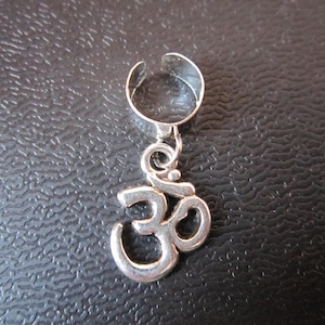 May include: Silver Om symbol charm on a silver ear cuff.